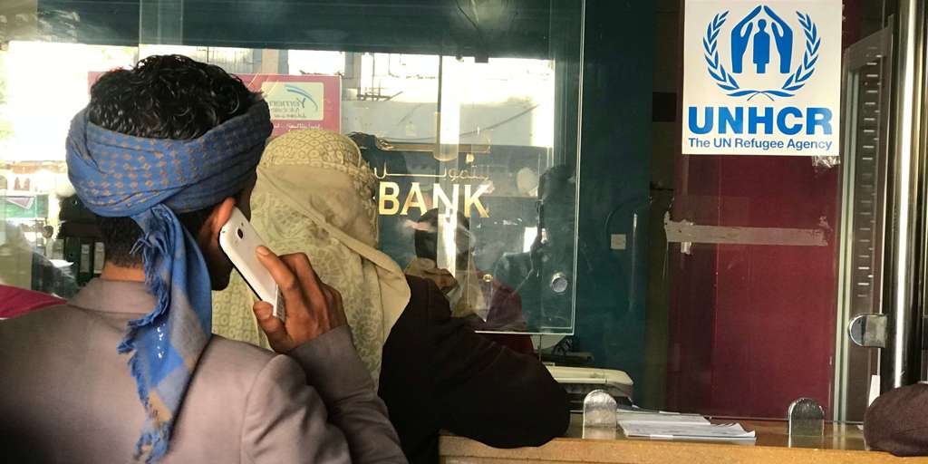Displaced Yemenis wait in line to receive a UNHCR cash rental subsidy at Al Amal Bank in Sana’a Yemen.