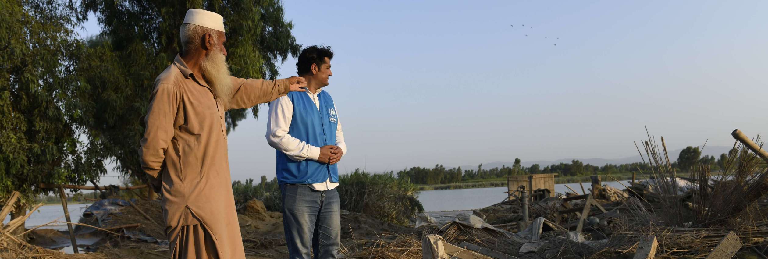 UNHCR workers and flood survivor survey damage in Khyber Pakhtunkhwa province, Pakistan.