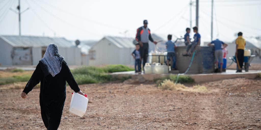 Syrian woman collects water in Jordan