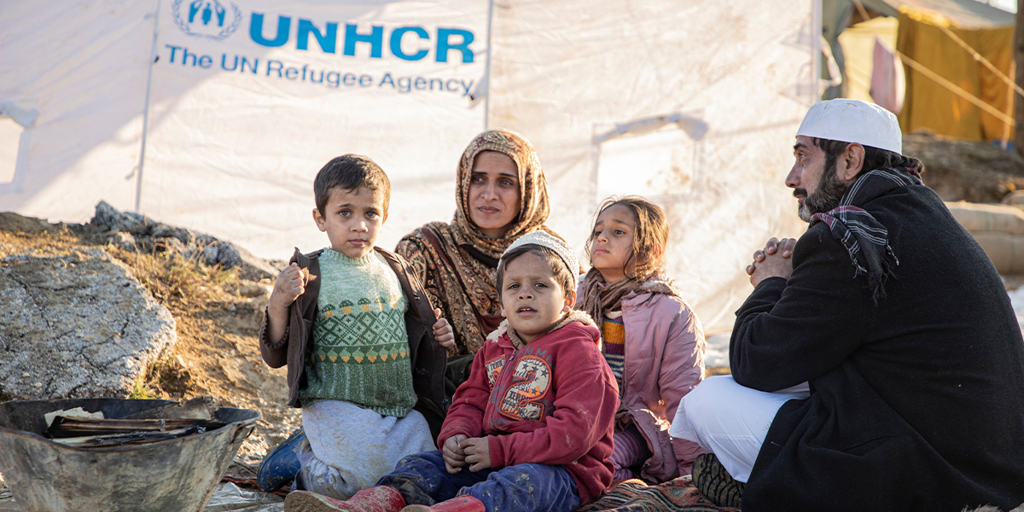 Family sits in front of UNHCR tent © UNHCR
