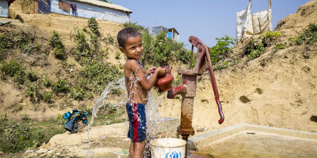 A Rohingya fills a bucket and kettle at a standpipe in Kutupalong camp.