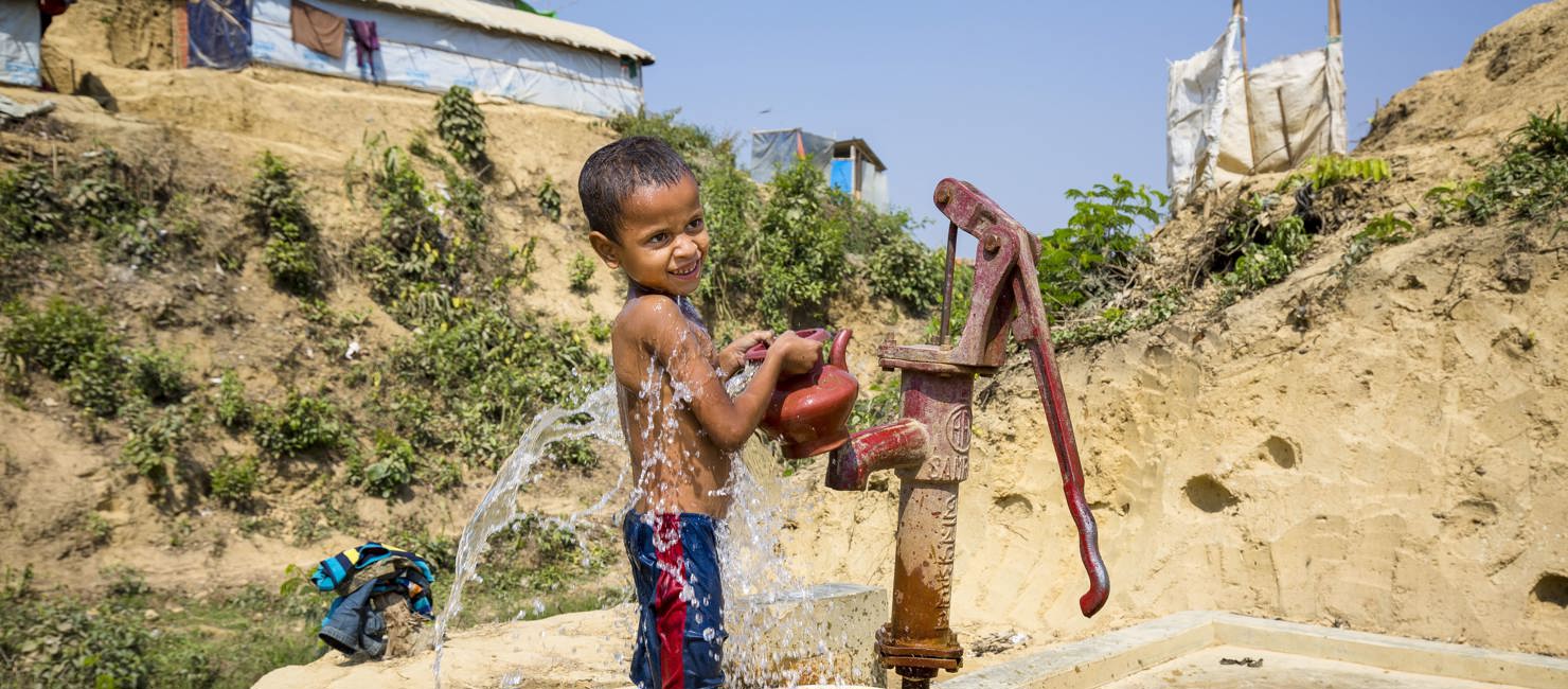 A Rohingya fills a bucket and kettle at a standpipe in Kutupalong camp.