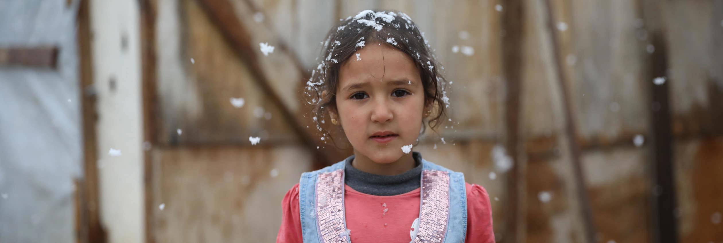  A Young girl stands in front of her tent while it snows in Beqaa valley.