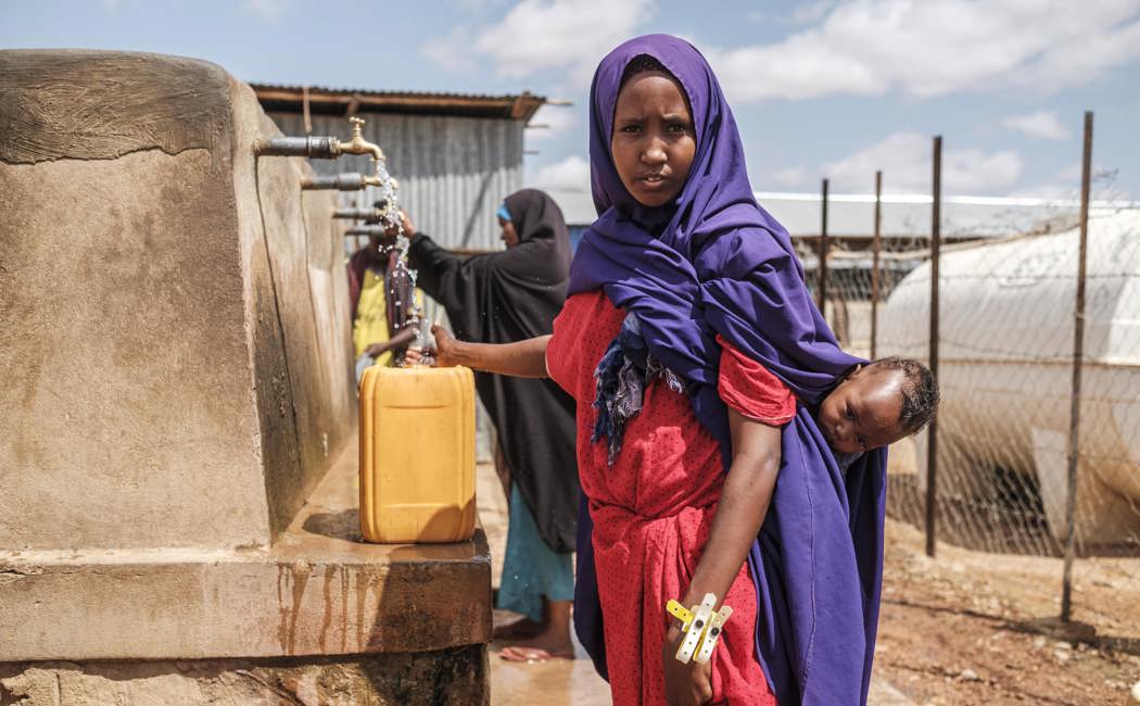 A Somali mother fills a jerry-can with water at UNHCR's reception centre in Dollo Ado, Ethiopia.