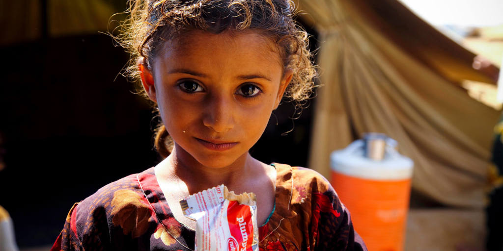 A young Yemeni girl eats a packet of Plumpy Nut, a high calorie food used in famine relief.