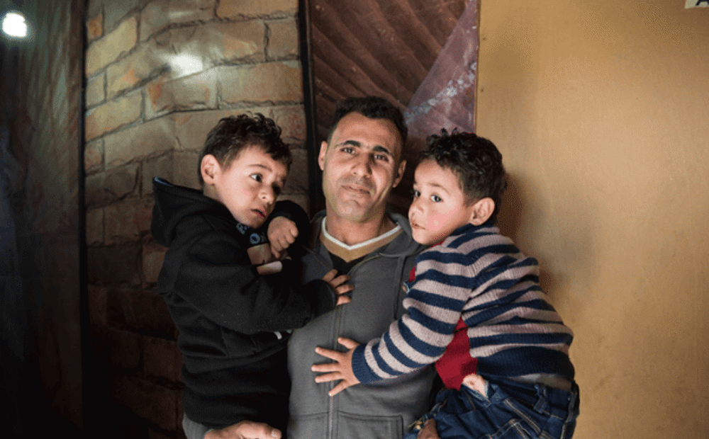A refugee father holds his two young sons