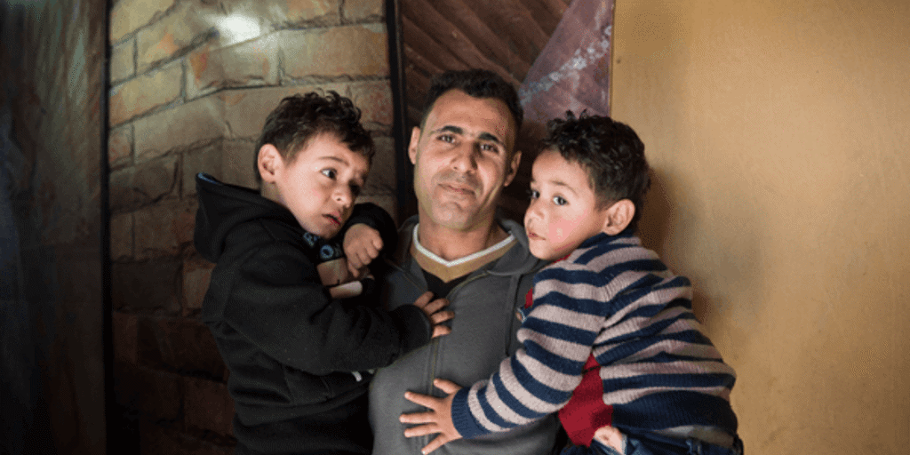 A refugee father holds his two young sons