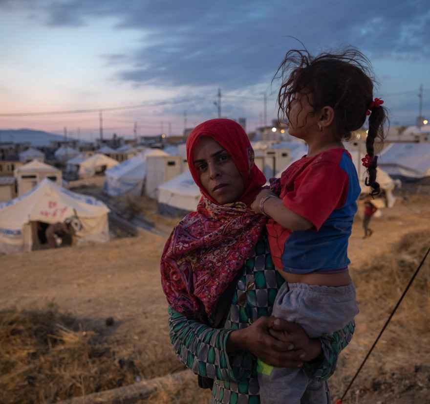 Rojin Ibrahim Davoud, a 28-year-old mother of four, holds one of her children outside a tent in Bardarash camp in Duhok, Iraq.