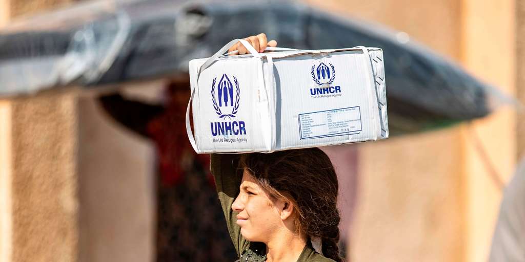 Displaced Syrians, who fled their homes in the border town of Ras al-Ain, receive humanitarian aid on October 12, 2019, in the town of Tal Tamr in the countryside of Syria's northeastern Hasakeh province.