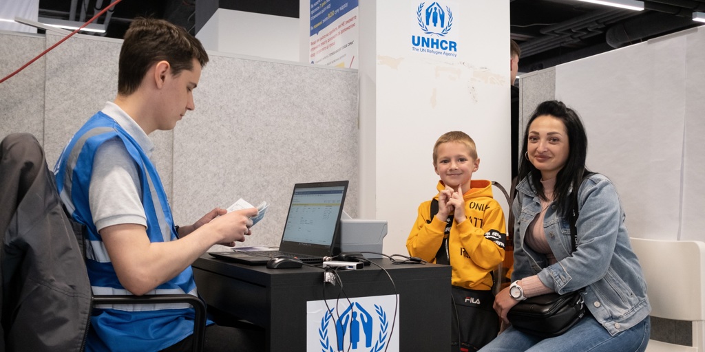 Yulia and her son wait at UNHCR's cash enrolment centre in Poland. They fled their home in Ukraine in March. 
